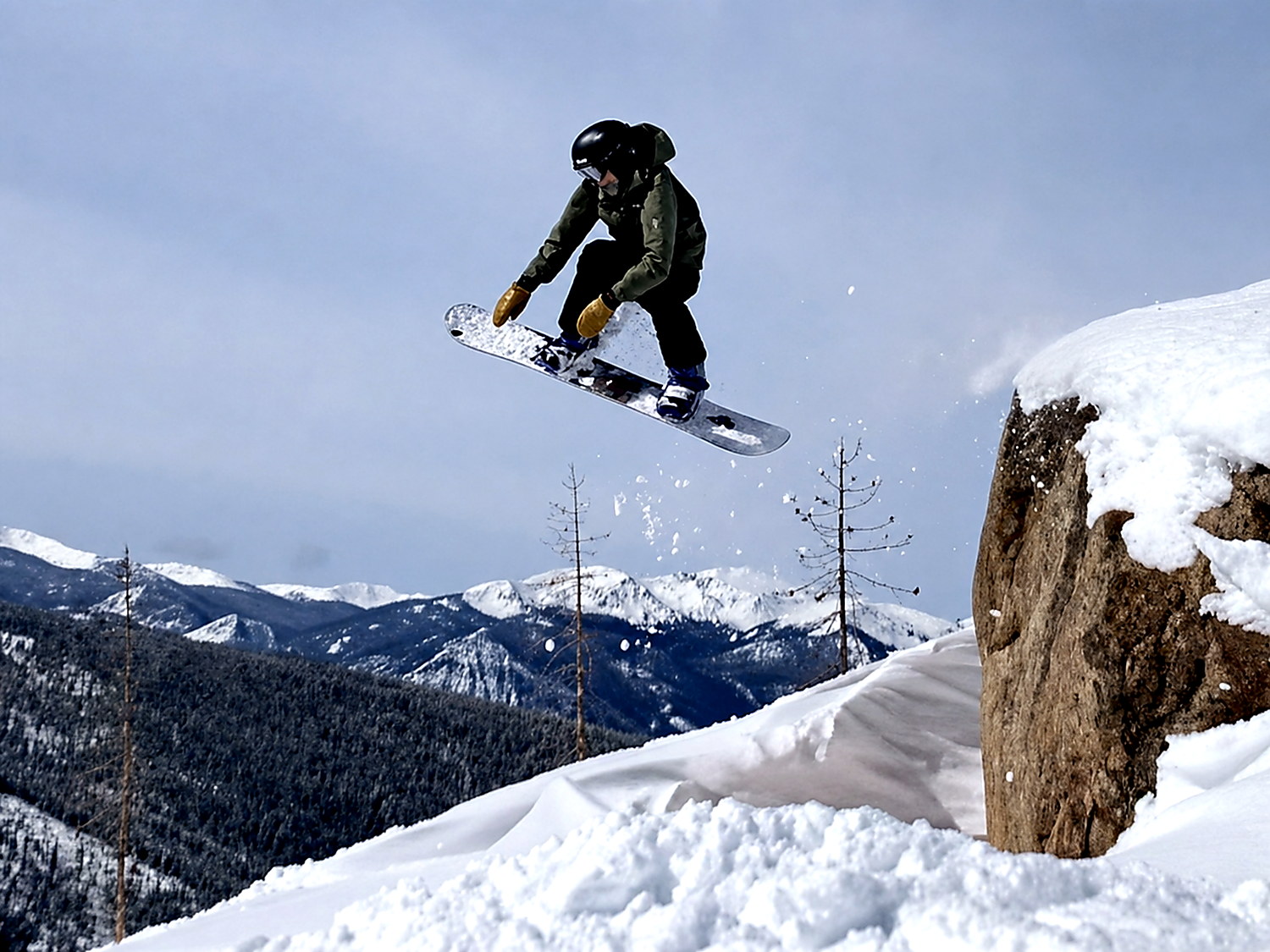 Snowboarder jumping above a snowy mountain slope